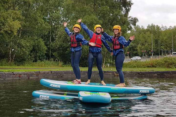Three girls balancing on three stand up paddle boards