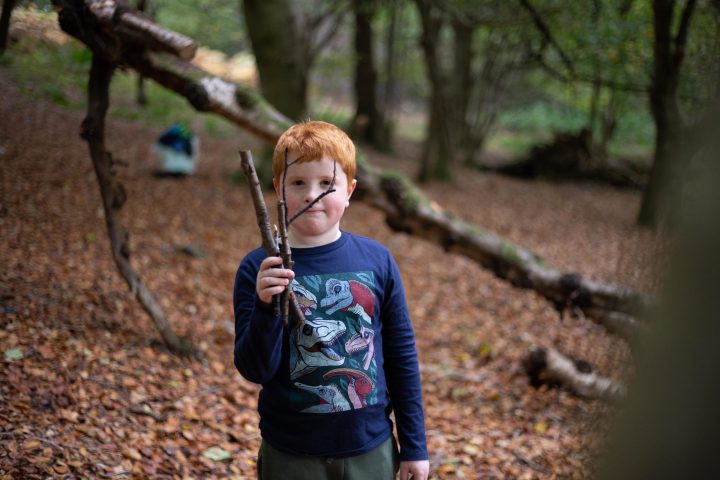 a little boy standing next to a forest